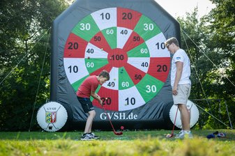 Ein Junge spielt einen Golfball auf eine große aufblasbare Dartscheibe